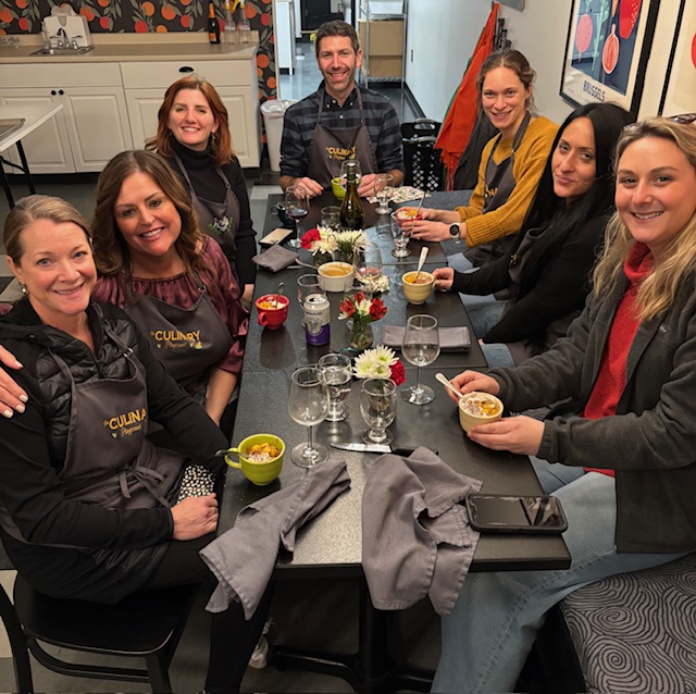 Group of people smiling around table with food in hand