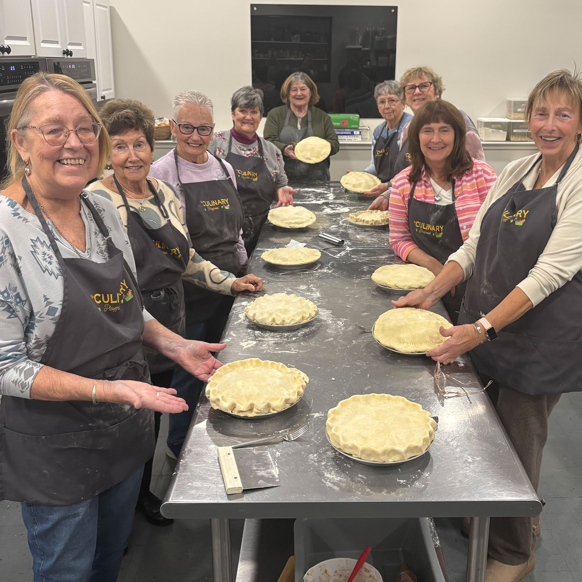 Women around the table smiling with pies