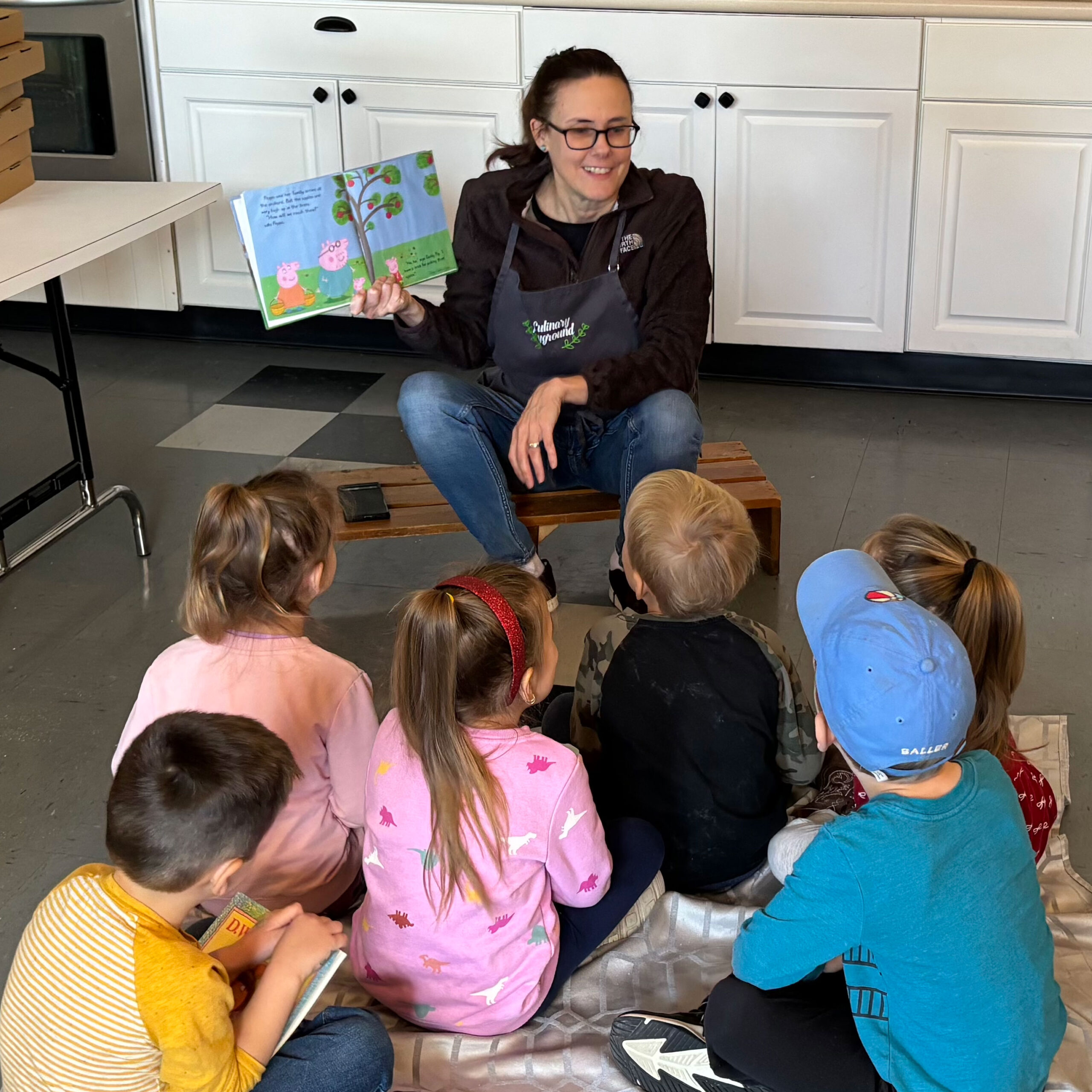 Woman sitting on bench reading book to children