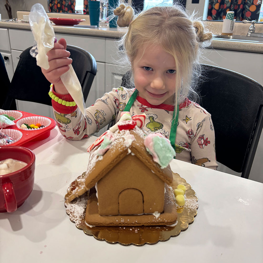 Young girl smiling while decorating gingerbread house